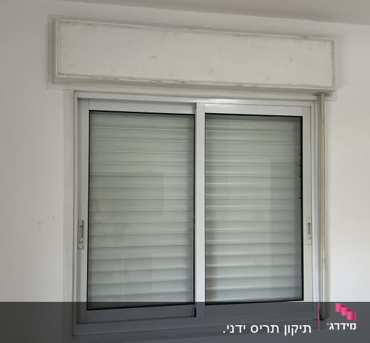 חלון עם תריסים סגורים על קיר לבן